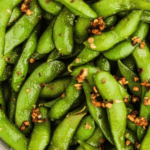 Close-up view of spicy edamame beans sprinkled with red pepper flakes.
