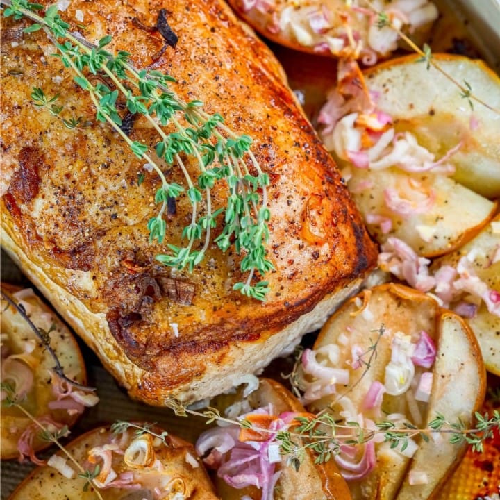picture of pork loin in a roasting dish with roasted pears, shallots, and rosemary