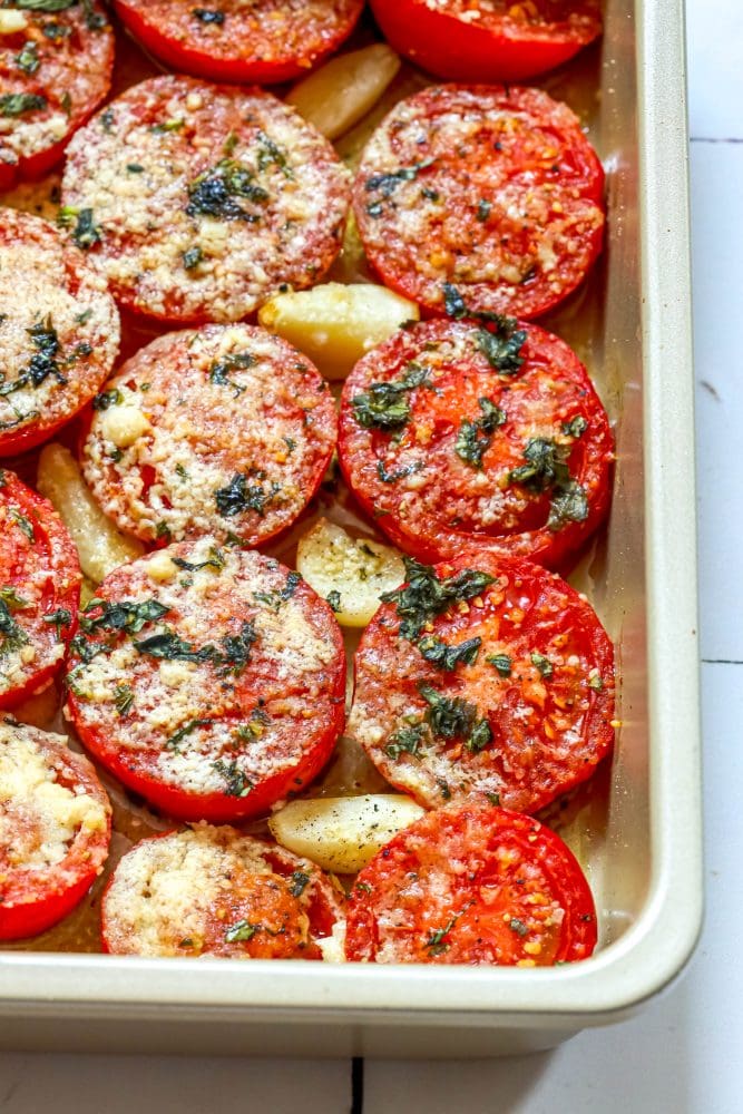 tomatoes in a casserole dish with garlic, basil, and parmesan cheese