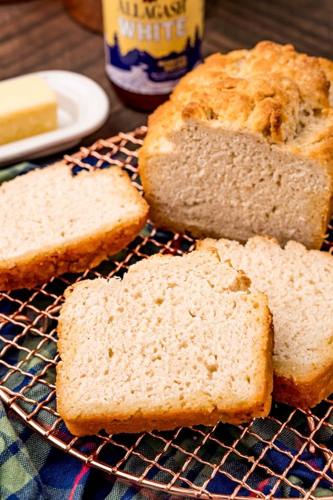 beer bread on a cooling rack in front of a bottle of beer