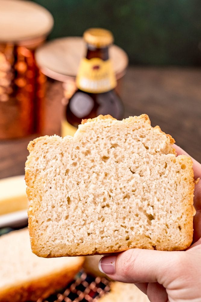 a hand holding a slice of beer bread
