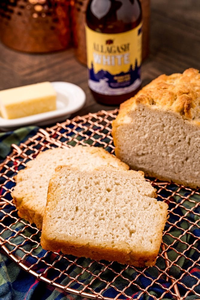 beer bread on a cooling rack in front of a bottle of beer