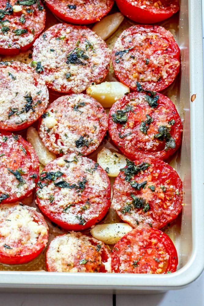 tomatoes in a casserole dish with garlic, basil, and parmesan cheese