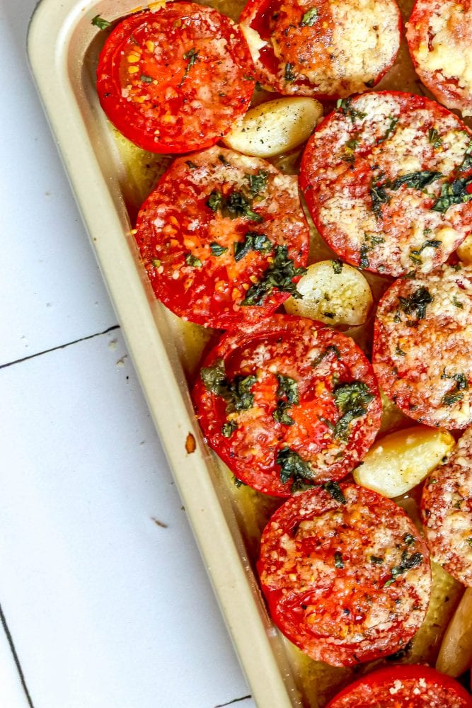 tomatoes in a casserole dish with garlic, basil, and parmesan cheese