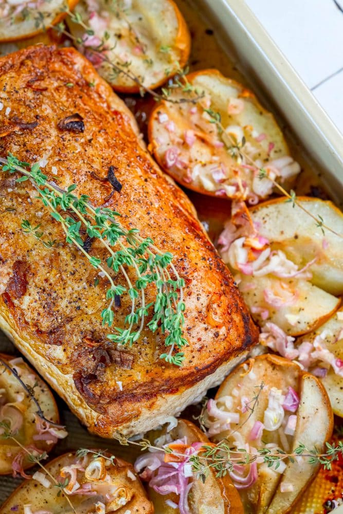 pork loin in a roasting dish with roasted pears, shallots, and rosemary