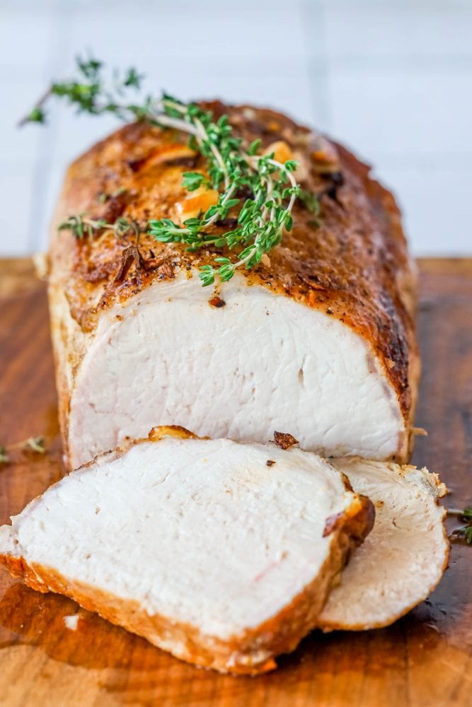 pork loin on a cutting board with shallots, and rosemary