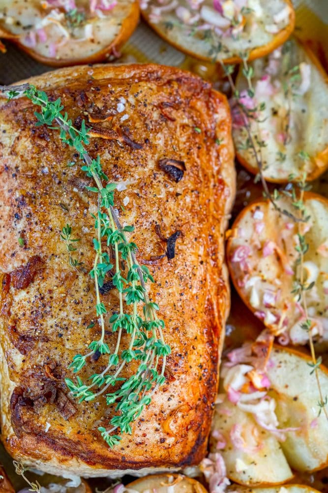 pork loin in a roasting dish with roasted pears, shallots, and rosemary