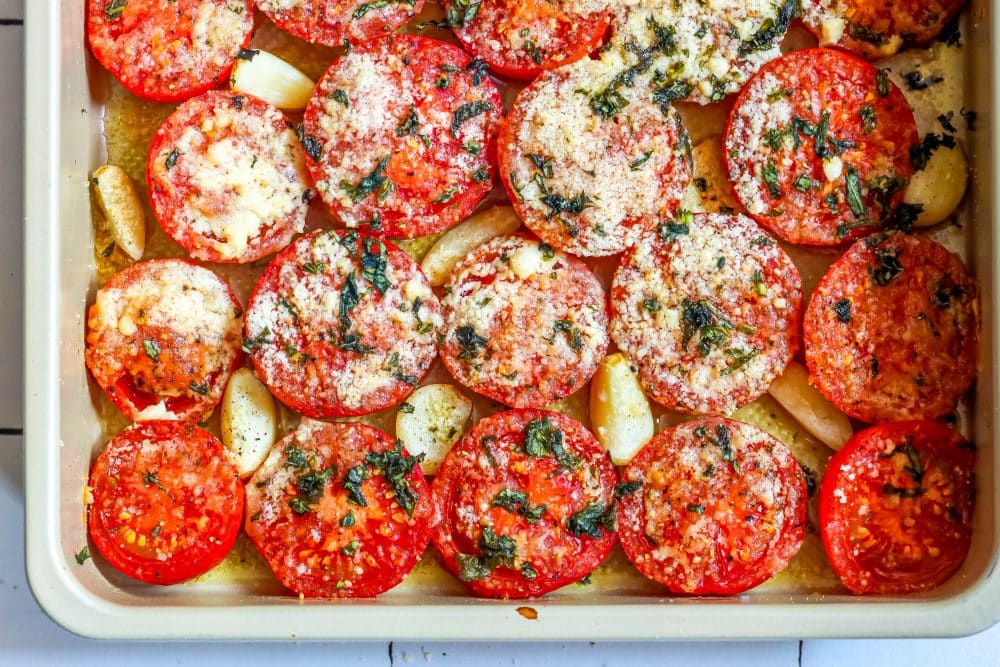 tomatoes in a casserole dish with garlic, basil, and parmesan cheese