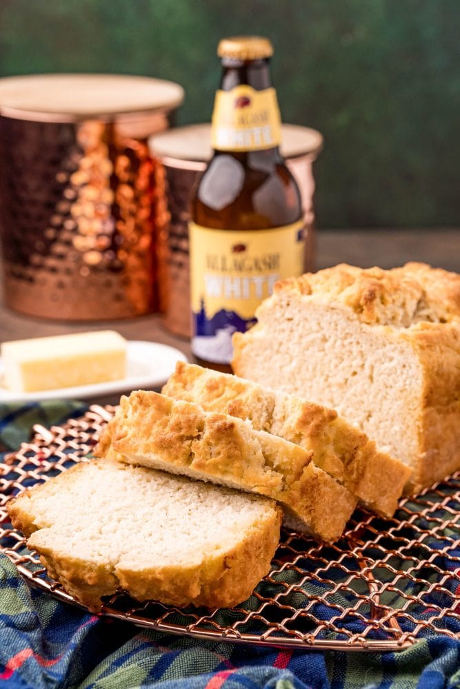 beer bread on a cooling rack in front of a bottle of beer