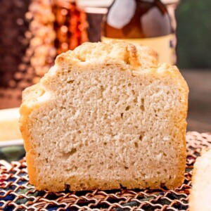 picture of beer bread on a cooling rack in front of a bottle of beer