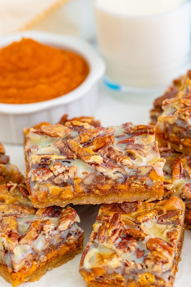 picture of pumpkin pie bars with pecans and a cookie base stacked together on a table