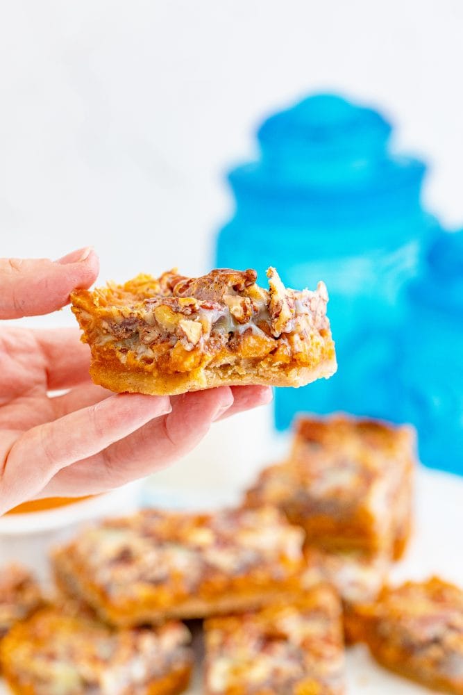 picture of pumpkin pie bar with pecans and a cookie base in a hand