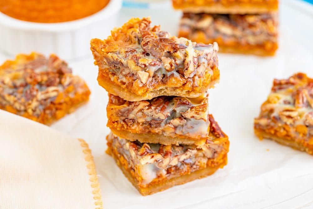 picture of pumpkin pie bars with pecans and a cookie base stacked together on a table