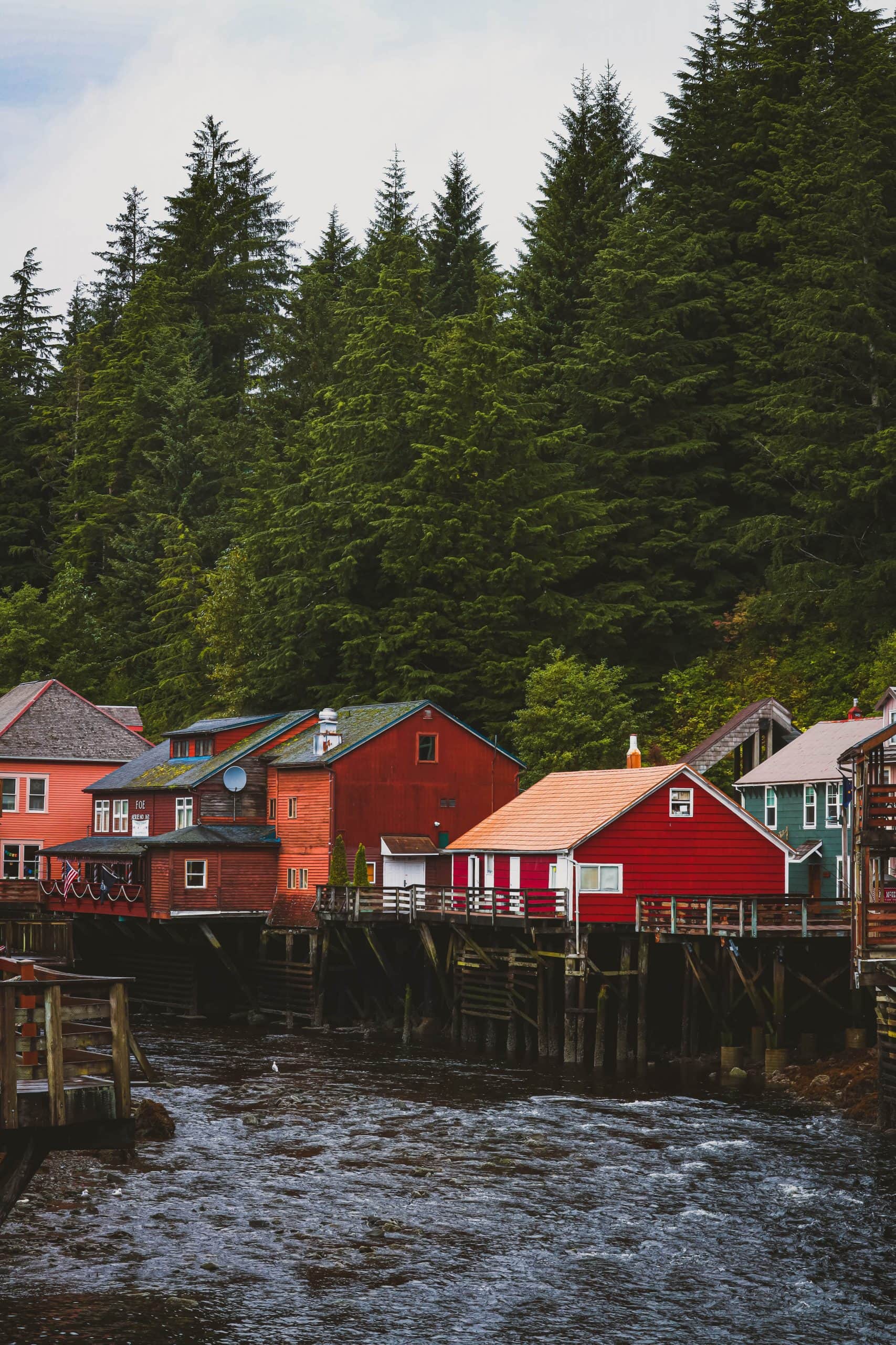 A group of red houses on the shore of a body of water near Princess Cruises Alaska.