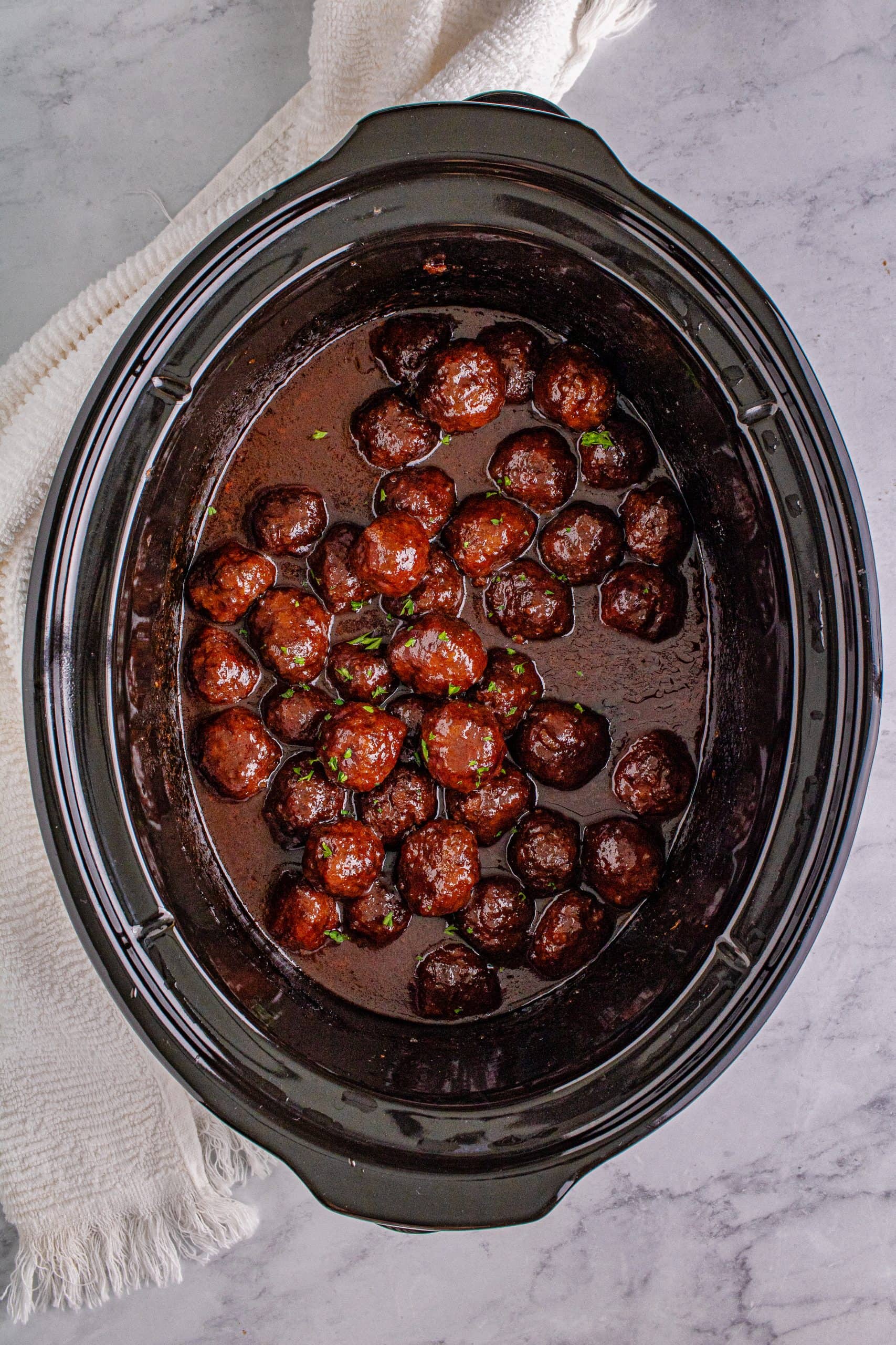 A crock pot filled with grape jelly meatballs.