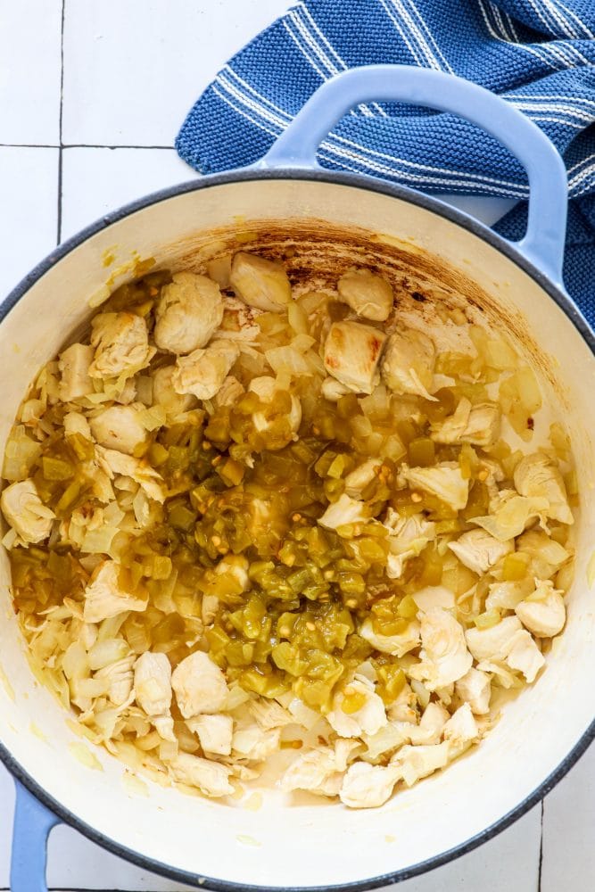 picture of diced chicken green chilies and browned onions in a dutch oven pan