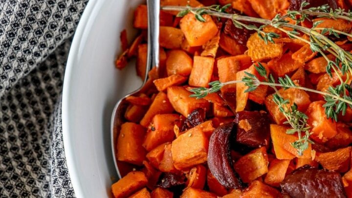 picture of roasted beets and sweet potatoes in a glass dish with thyme on top