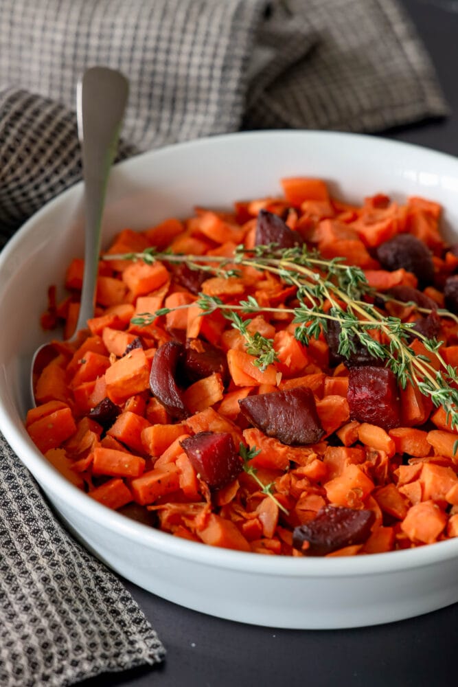 picture of roasted beets and sweet potatoes in a glass dish with thyme on top 