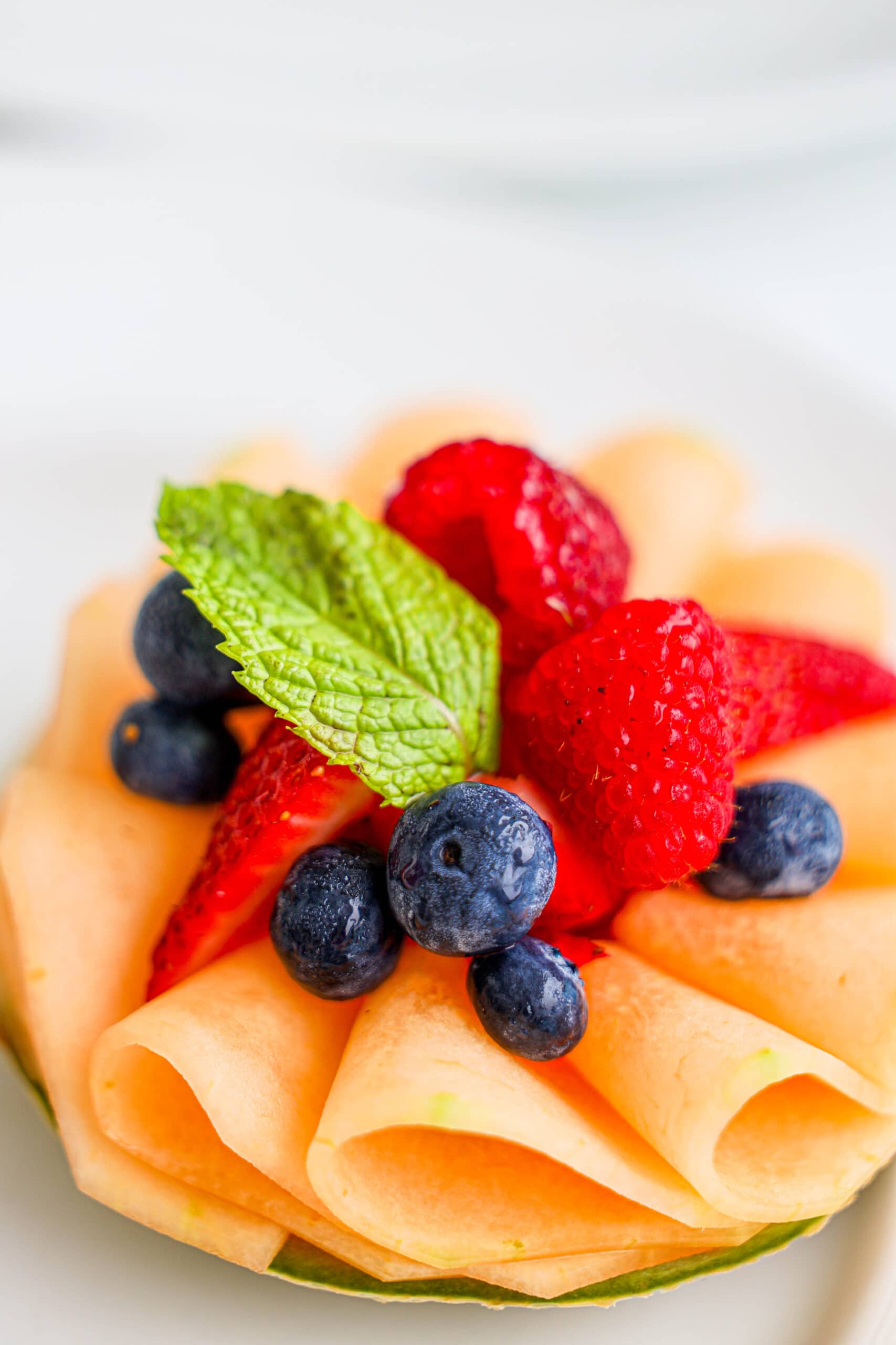 Your Ultimate Dining Guide for the Majestic Princess 44 A vibrant plate of fresh fruit adorned with juicy berries and a delicate mint leaf, perfect for indulging in the gourmet cuisine of Princess Cruises’ Majestic Princess.