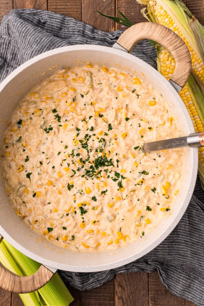 picture of corn chowder with shredded chicken in a stock pot with parsley on top