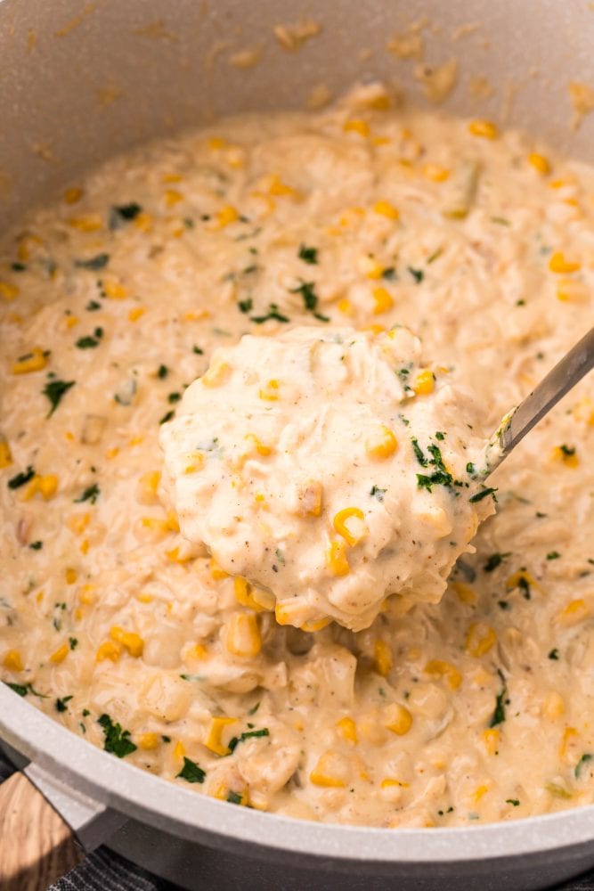 picture of a spoon scooping up a spoonful of corn chowder in a pot