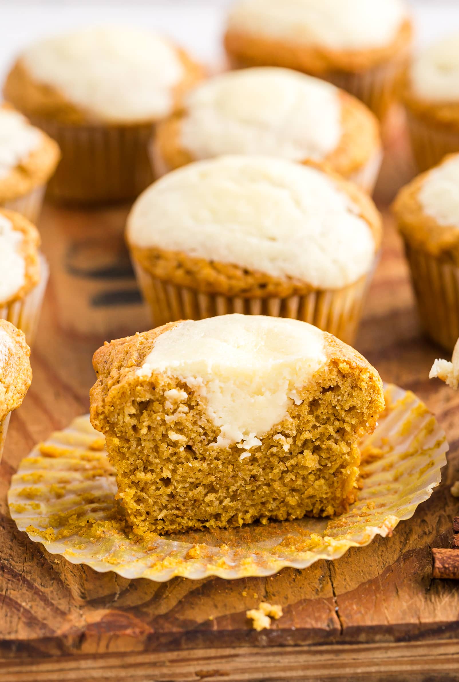 Pumpkin cupcakes with cream cheese frosting on a wooden cutting board: Cream cheese pumpkin muffins.