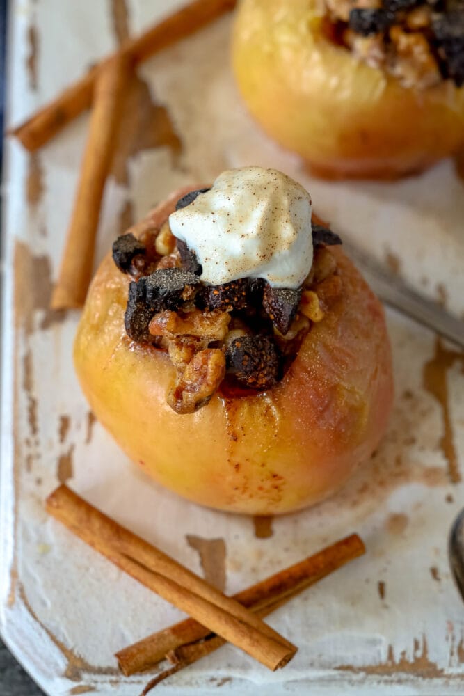 picture of baked apple on a plate topped with figs and whipped cream