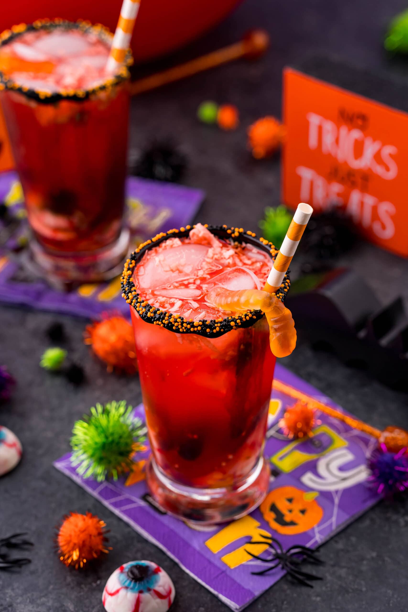 Two glasses of sparkling Halloween fruit punch with candy and decorations.