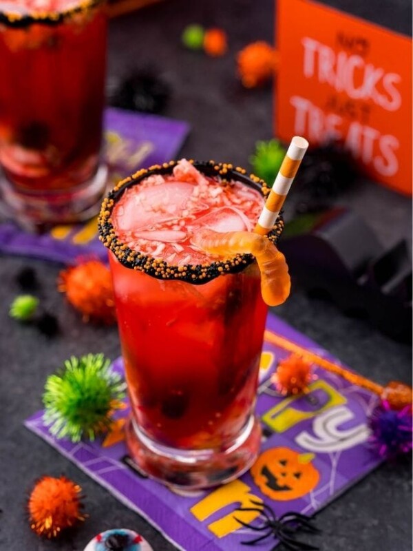 picture of halloween punch with gummy worms on a table with halloween party decorations