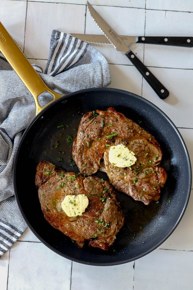 picture of ribeye steak with a pat of clarified butter in a pan 