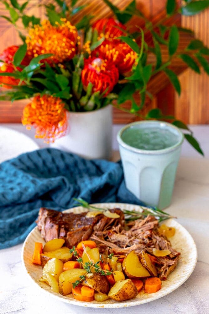 picture of shredded pot roast, potatoes, carrots, and fresh thyme on a plate