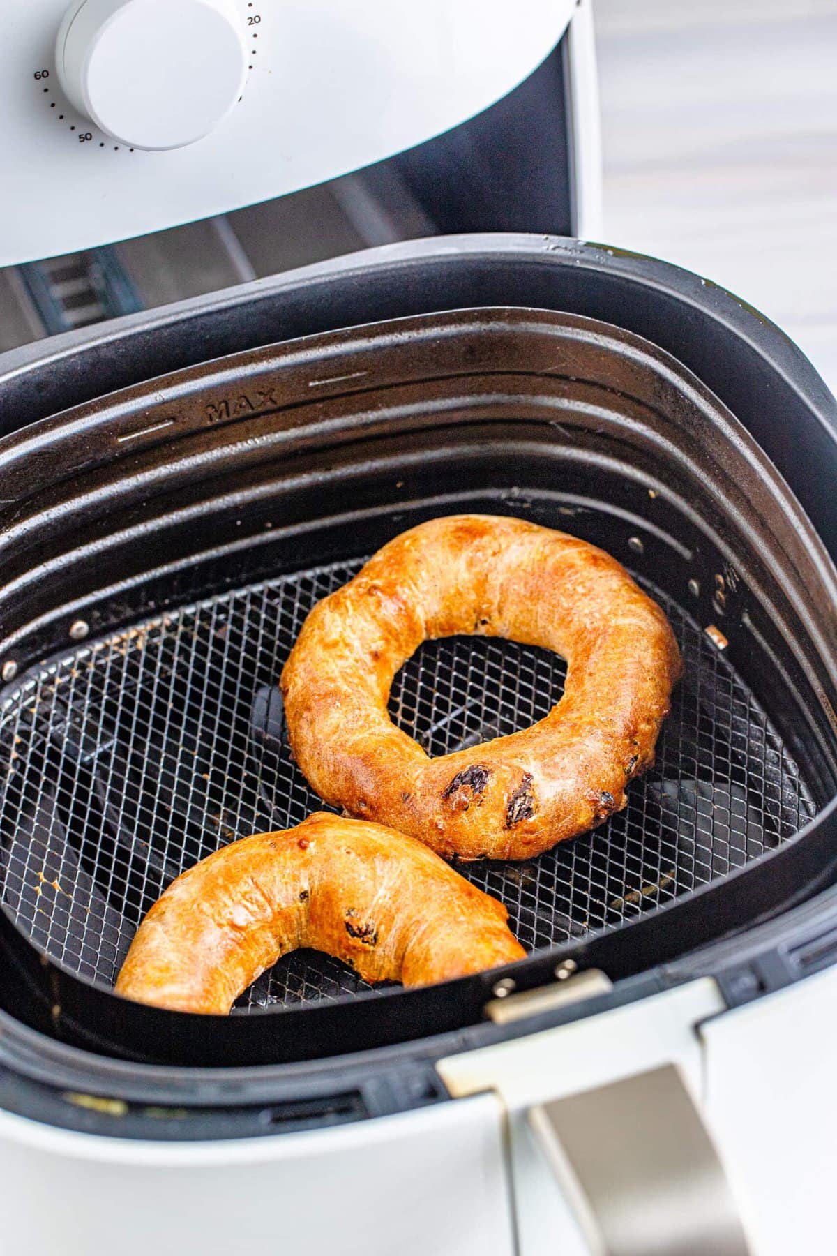 Two cinnamon raisin bagels cooked in an air fryer.