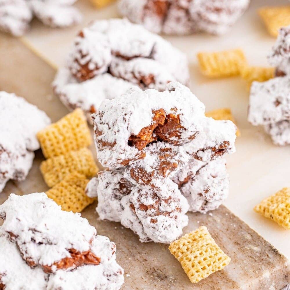 picture of muddy buddy cookies stacked on a wood cutting board