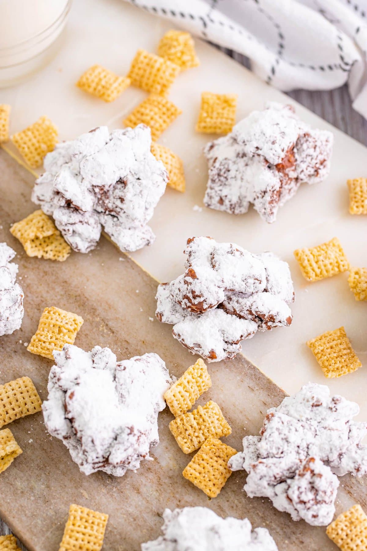 Powdered cranberry krispy treats resembling Muddy Buddy Cookies on a cutting board.