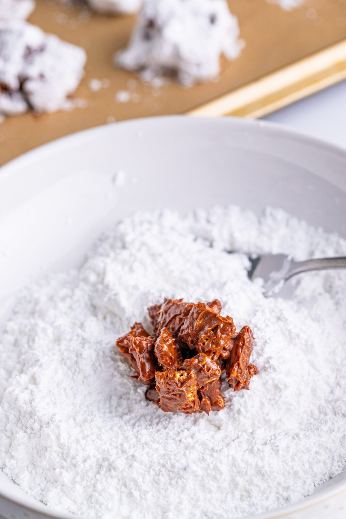picture of muddy buddy cluster being dipped in powdered sugar