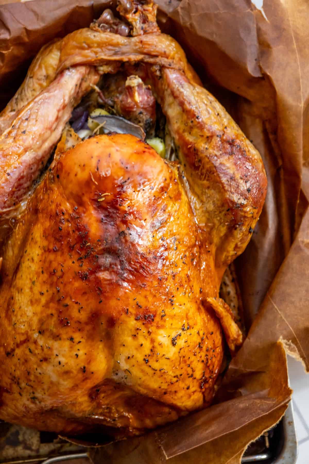 Roasted turkey with crispy, golden-brown skin on parchment paper, seasoned with herbs—try this easy Brown Bag Herb Roasted Turkey Recipe for perfectly juicy meat.