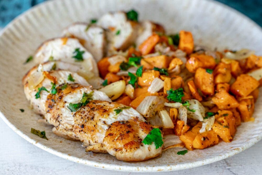 picture of turkey tenderloin on a plate with sweet potatoes and onions