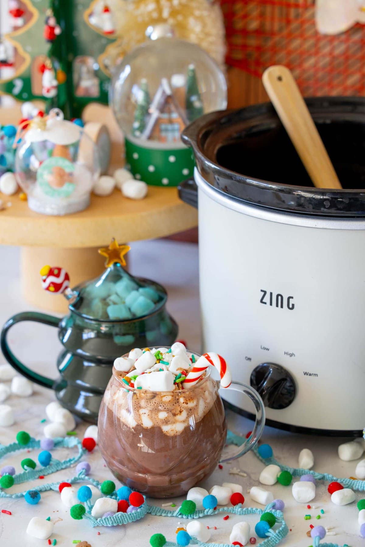 Rich and Creamy Slow Cooker Hot Chocolate 12 A festive mug of rich homemade hot cocoa, complete with a candy cane stirrer and mini marshmallows, set against a warm, inviting backdrop.