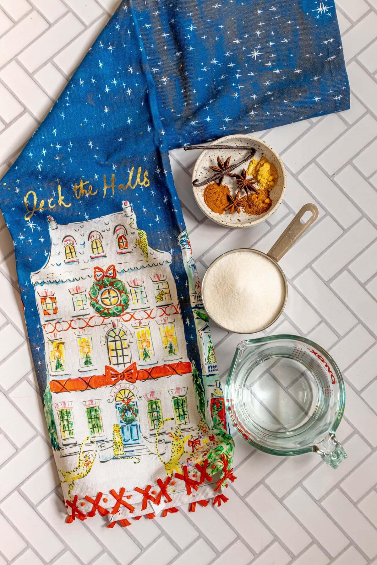 A tea towel with a Christmas house and spices, including mulling spice simple syrup.
