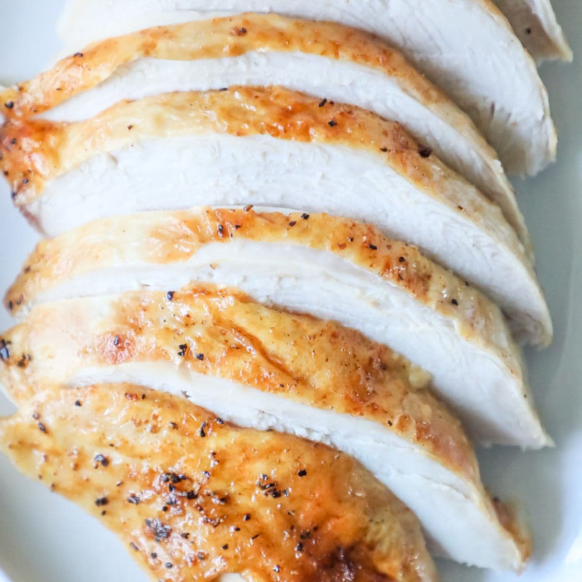 Sliced chicken breasts on a white plate, Oven Baked Chicken Breasts.