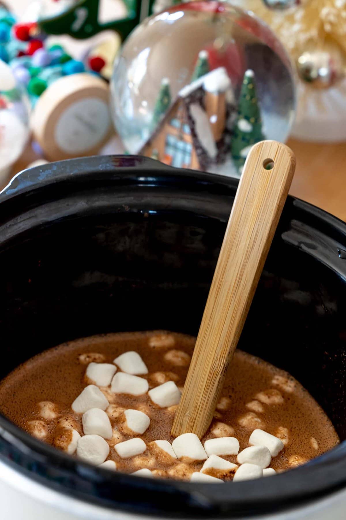 A slow cooker filled with homemade hot cocoa made with chocolate and marshmallows.