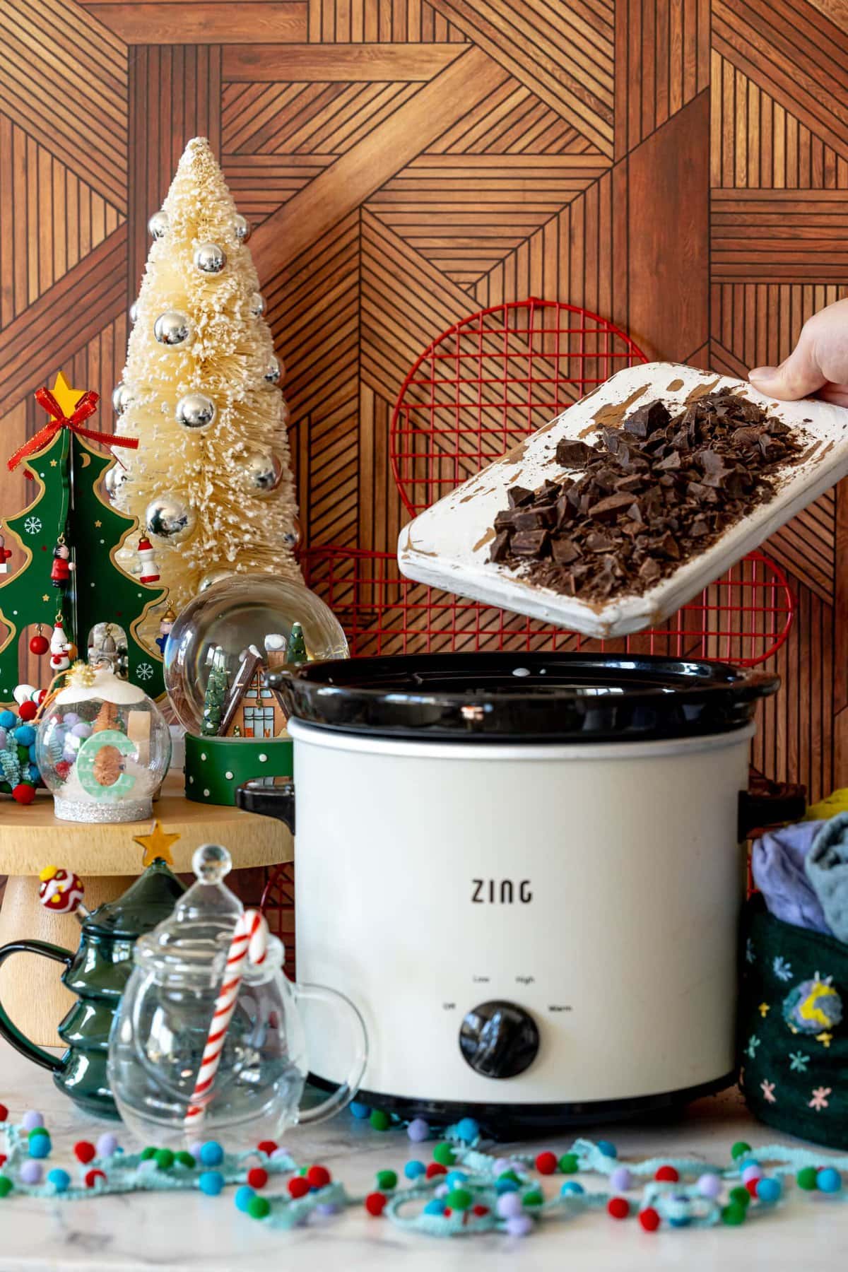 Rich and Creamy Slow Cooker Hot Chocolate 6 A hand adding chocolate chunks to the slow cooker with milk, starting the hot chocolate creation process.