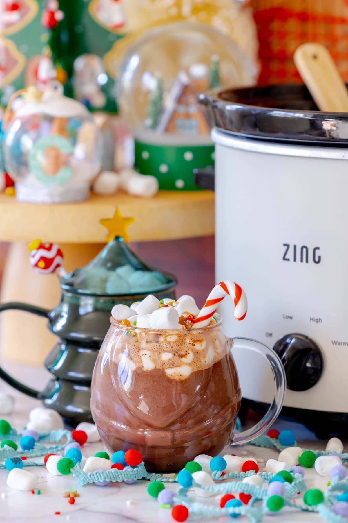 Rich and Creamy Slow Cooker Hot Chocolate 3 A festive mug of homemade slow cooker hot chocolate, adorned with a candy cane stirrer and mini marshmallows.