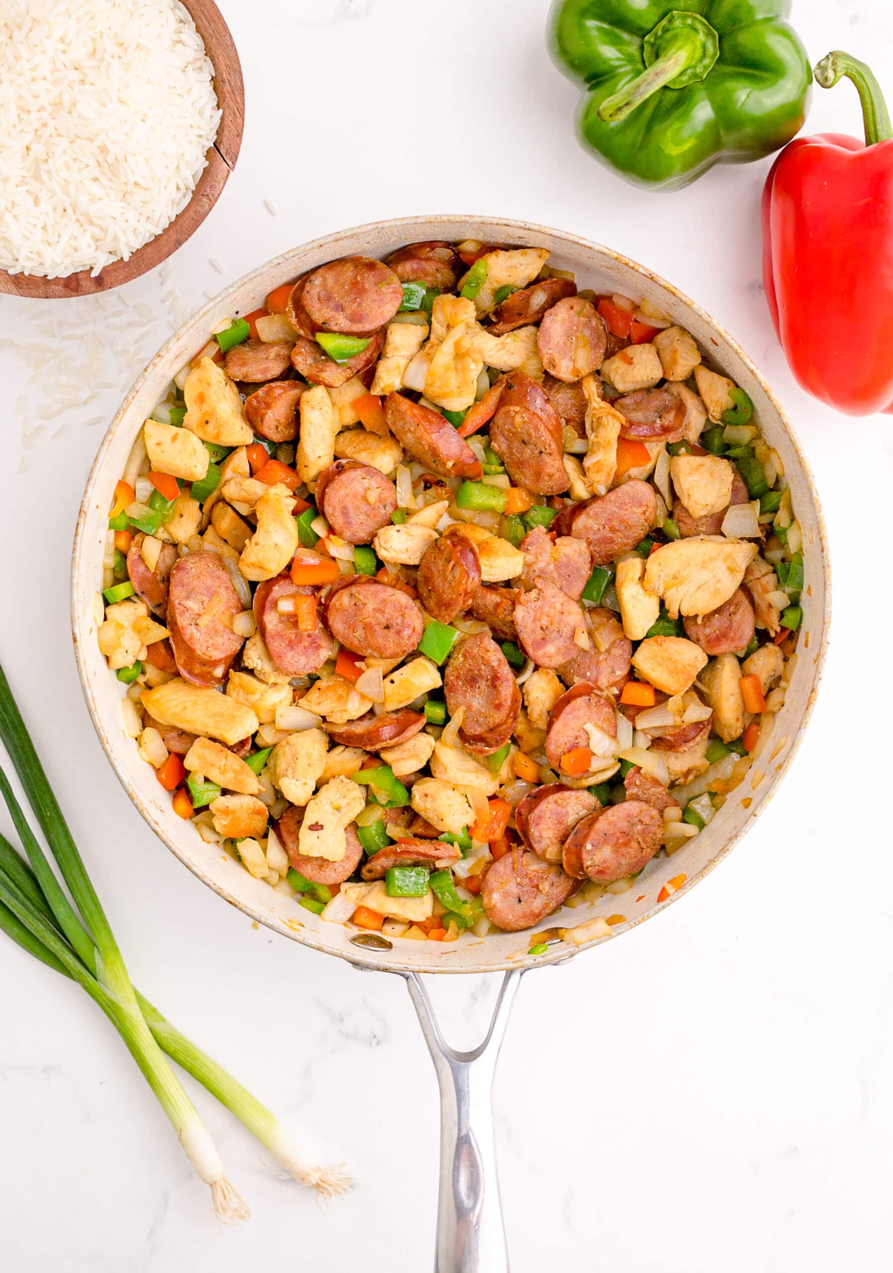 picture of chicken and sausage and vegetables browning in a pan