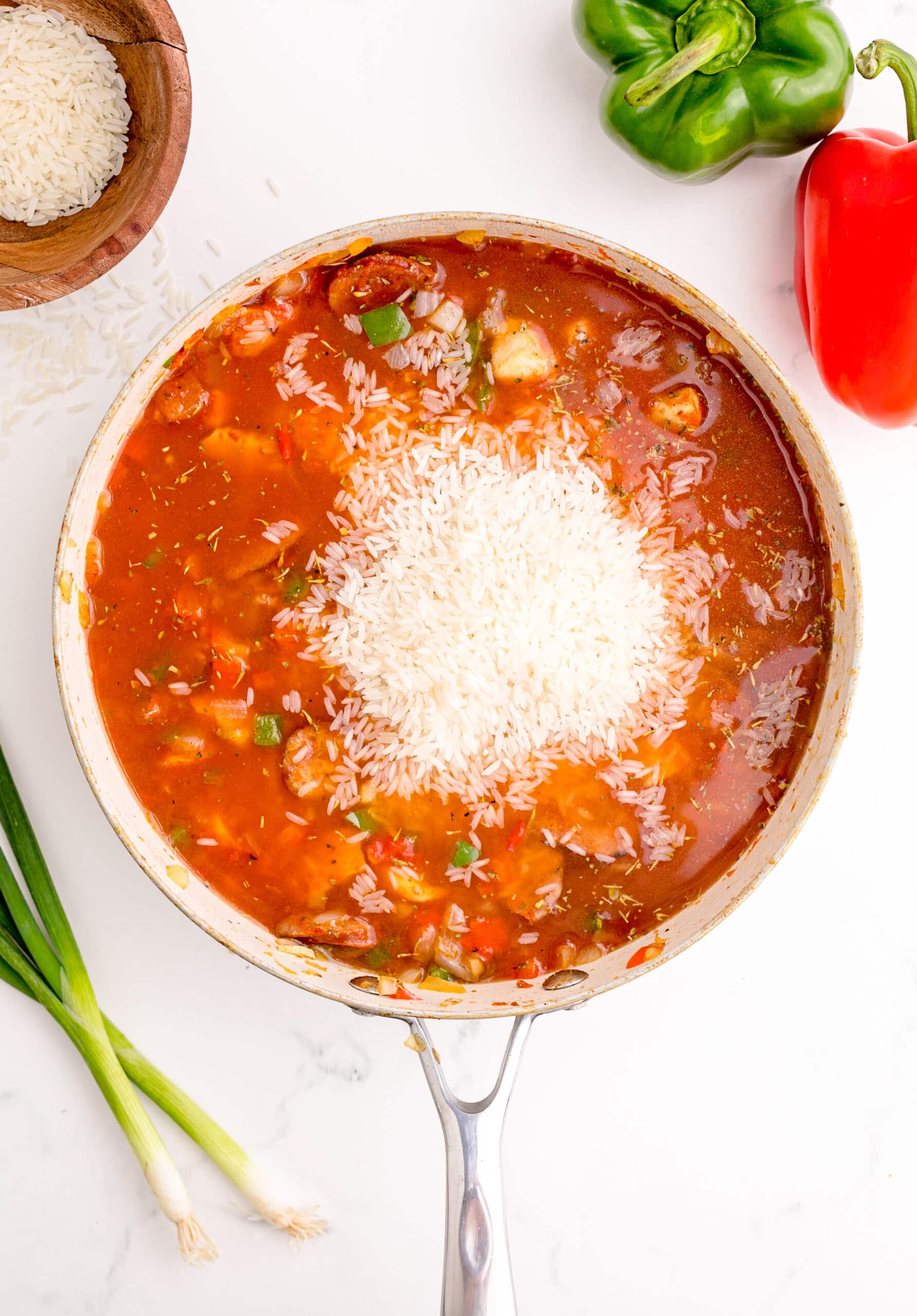 picture of jambalaya base simmering in a pan with rice on top