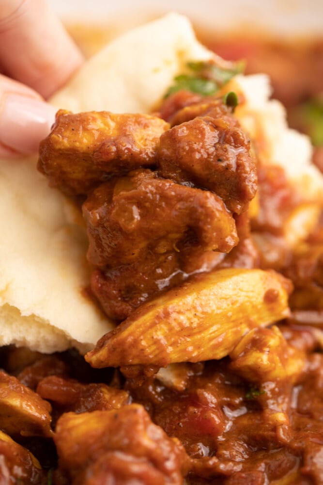 picture of hand scooping madras curry with naan bread