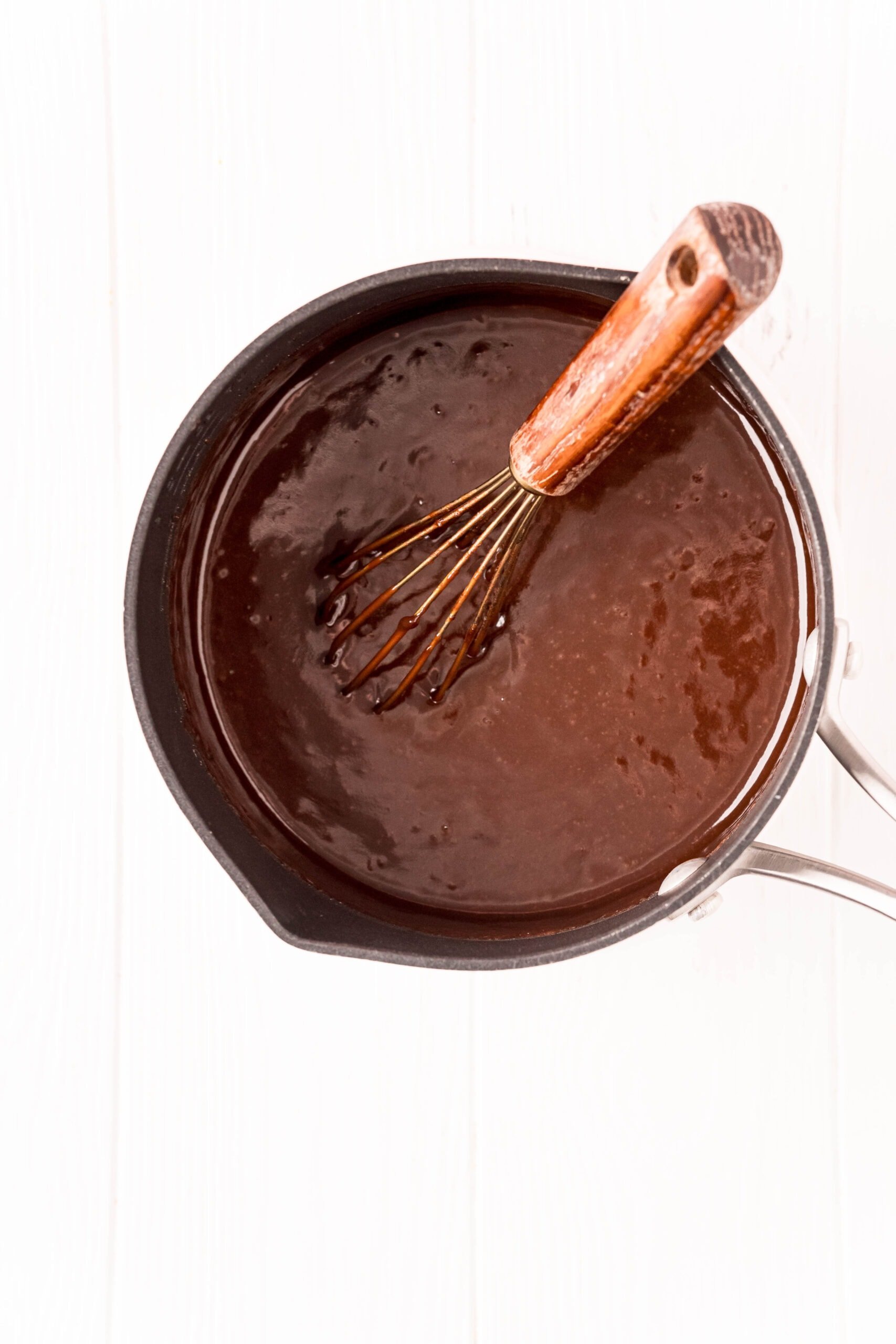 picture of cocoa and butter melted in a saucepan with a whisk
