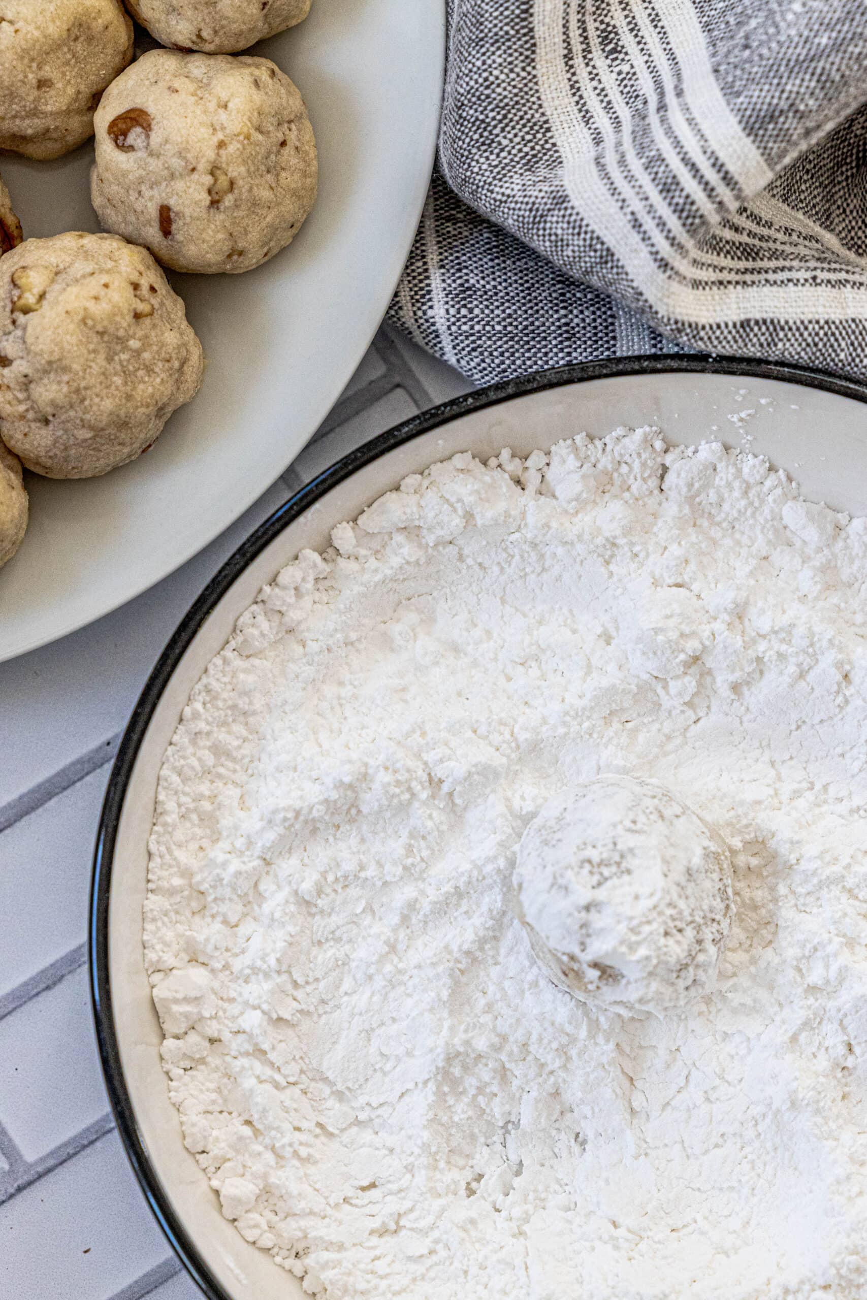 picture of cookie being rolled in powdered sugar