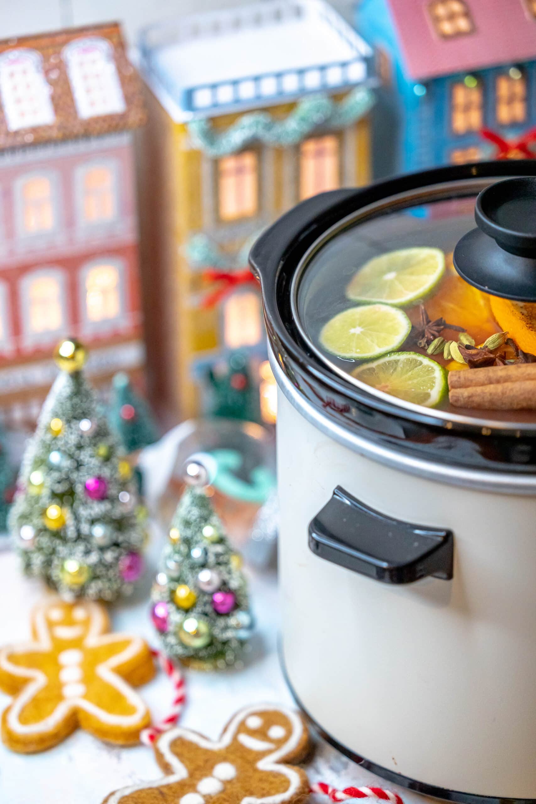 A slow cooker with gingerbread cookies and gingerbread men, accompanied by a mulled citrus cider.
