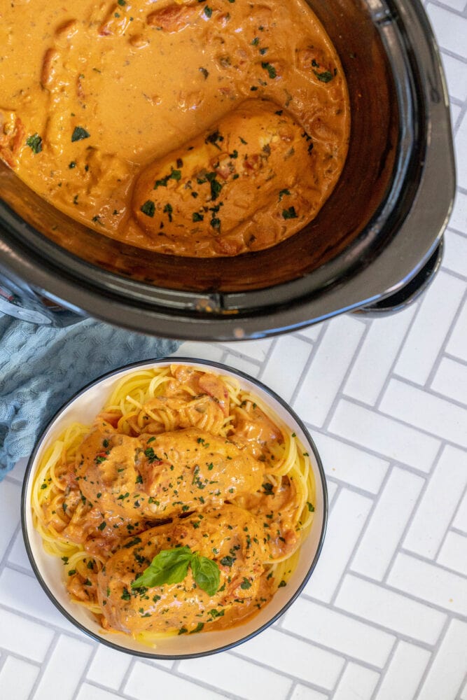 picture of creamy tomato basil chicken breasts in a bowl over pasta